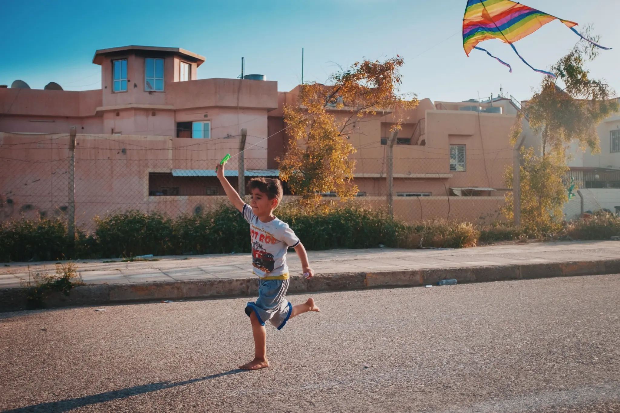 A child running with a kite through a village